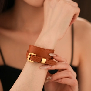 Detail of a brown faux leather double wrap bracelet featuring a classic gold metal buckle