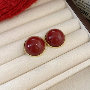 Dettaglio di orecchini vintage tondi rossi con placcatura in oro nel portagioie