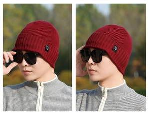 Detail view of burgundy ribbed knit beanie with side logo tag worn outdoors