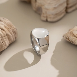 Gros plan d'une bague en acier argenté avec pierre naturelle blanche ovale sur pierre