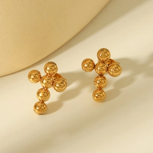 Macro detail of golden metallic ball stud earrings in a cross shape design