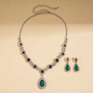 Close-up of vintage silver necklace and teardrop green crystal earrings set