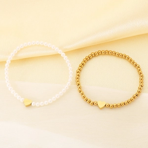 Detailed macro view of elegant pearl and gold beaded bracelets with golden heart charms