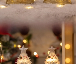 Close-up of golden embossed base and white snowflake Christmas tree with warm LED lights
