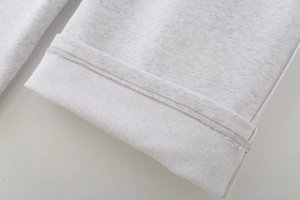 Detail shot of the frayed hem and fleece fabric texture on grey sports sweatpants