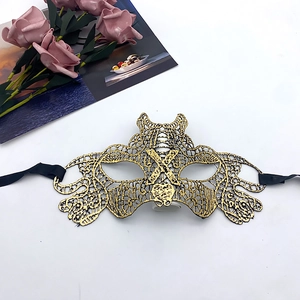Close-up of golden lace masquerade mask with intricate floral embroidery and black ribbons