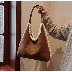 Detail of suede tote bag with white plush trim and shoulder strap in soft light