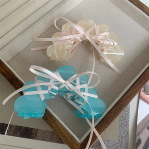 Detail of pink and blue acetate hair claws with ribbons in a wooden jewelry tray