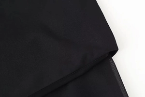 Detail of black fabric with translucent mesh splicing and refined stitching on a dress