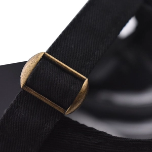 Detail of adjustable cotton strap with antique bronze metal buckle on black baseball cap