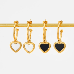 Close-up of gold heart earrings with white mother-of-pearl and black enamel inlays