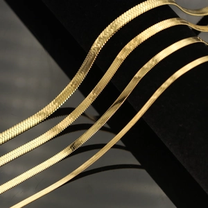 Detail view of four graduated golden snake chains on a black velvet jewelry display stand