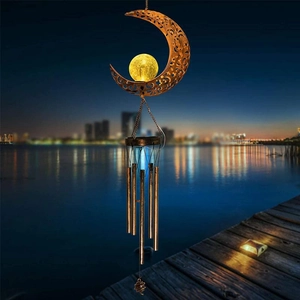 Solar moon wind chime with bronze metal hollow design glowing on an outdoor terrace at night