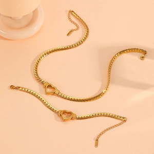 Golden titanium steel jewelry set with heart pendants and cuban chain on pink background