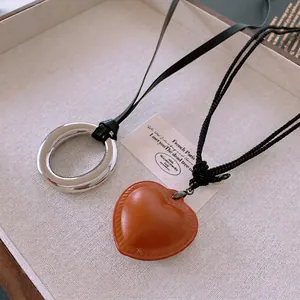 Minimalist faux leather heart pendant and metal ring necklace on jewelry tray