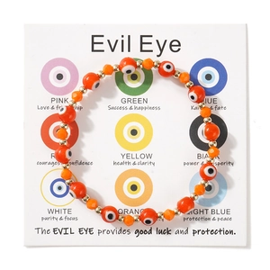 Λεπτομέρεια από πορτοκαλί βραχιόλι Evil Eye με χρυσές χάντρες σε κάρτα δώρου με νόημα