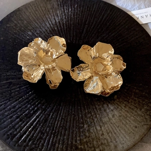 Detail shot of 3D pleated metal flower earrings with shiny gold mirror finish