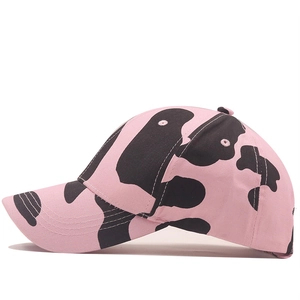 Detail side view of pink and black cow print baseball cap with curved brim and top button