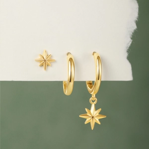 Detailed macro view of gold octagonal star stud and hoop earrings set on green stand