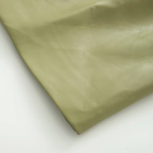 Detail of olive green PU leather fabric showing smooth matte texture and natural grain