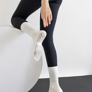 Detail of white yoga socks with grey anti-slip silicone grips on the sole for pilates