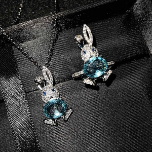 Detail of bunny pendant with micro-paved diamonds and oval blue topaz on black silk