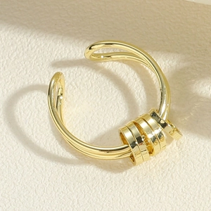 Detailed close-up of golden wavy open ring featuring four sliding metal beads