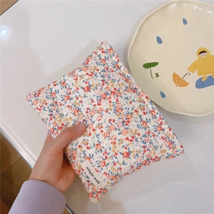 Detailed texture of quilted floral cotton fabric and woven label on a mini makeup pouch
