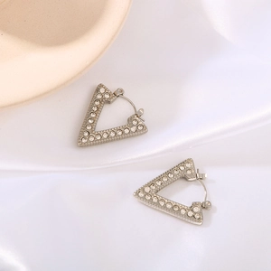 Silver-toned triangle stud earrings with shimmering rhinestones on white silk