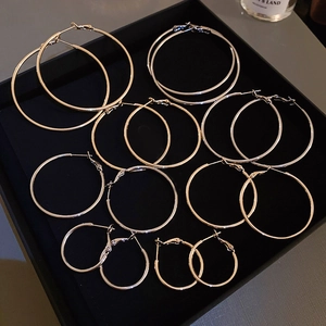 Set of gold and silver geometric hoop earrings in various sizes on a black display tray