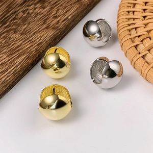 Minimalist spherical metal hoop earrings in gold and silver finish on white background