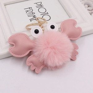 Detail of pink plush crab keychain with fluffy fur ball and golden metal lobster clasp