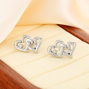 Close-up of interlocking silver heart stud earrings with sparkling zircon inlay