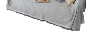 Close-up of grey waffle knit sofa cover with fringe details in a Nordic style setting