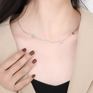 Gros plan du collier avec pendentif MAMA argenté porté par un mannequin élégant