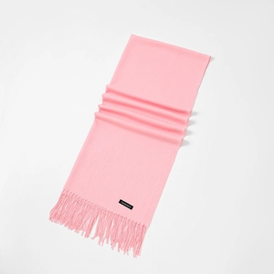 Detail of pink cashmere scarf showing soft texture, fringe tassels, and woven label