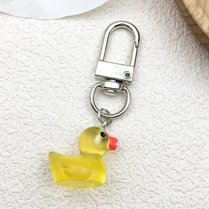 Close-up of a 3D yellow glowing resin duck charm with silver metal lobster clasp