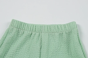 Gros plan sur la texture en seersucker vert clair et la taille élastique du pantalon