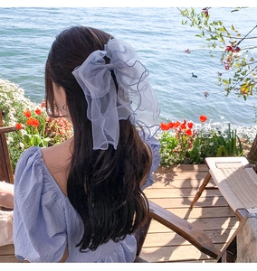 Close-up of a blue oversized chiffon bow hair clip worn by a girl at the beach side