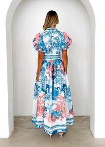 Back view of a long floral summer dress featuring puff sleeves and a belted waist design