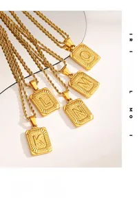 Détail de pendentifs lettres rectangulaires dorés avec chaîne torsadée sur miroir