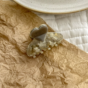 Detail shot of a heart-shaped acetate hair claw clip on brown paper background