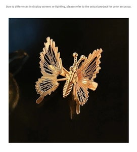 Detail of a gold butterfly hair clip featuring delicate woven wire wings on a black base