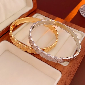 Detail of gold and silver quilted bangle bracelets with cubic zirconia on a velvet box
