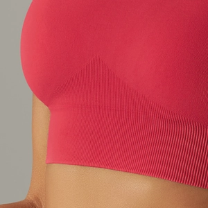 Detailed macro view of the seamless red sports bra featuring ribbed texture hem and stretch knit
