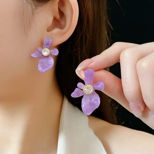 Détail de boucles d'oreilles fleurs en résine violette avec strass sur mannequin