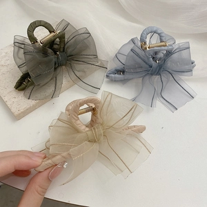 Elegant mesh bow hair claw clips in green, blue and champagne colors on stone tray