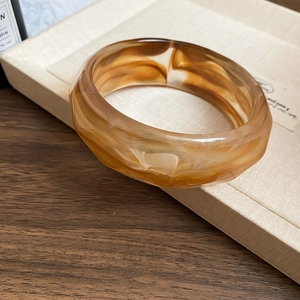 Bracciale largo in resina ambrata marmorizzata con bordi geometrici sfaccettati e stile