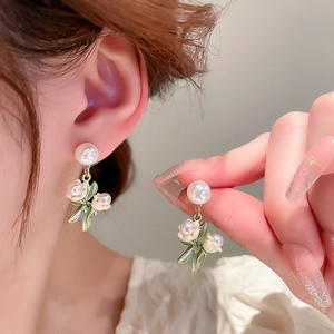 Détail de boucles d'oreilles muguet avec feuilles en émail vert et perles en tulipe