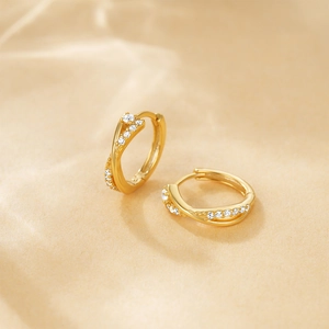Detailed view of gold twisted huggie hoop earrings with sparkling crystal pavé stones